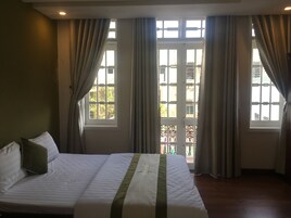 Quarto de hotel com cama, cortinas e vista pela janela.