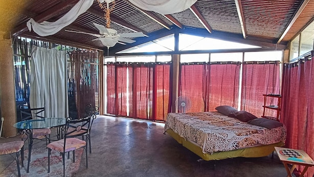 Una habitación con cama, una mesa, sillas y un ventilador de techo.