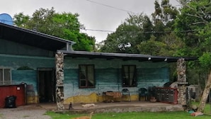 Una casa con un porche, un perro y un árbol.