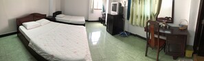 Une chambre d’hôtel avec un grand lit, un lit plus petit, un bureau, une chaise, une armoire, une télévision et un miroir.