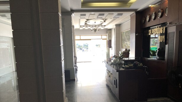 A hallway with a reception desk, a chandelier, and a view into the dining area. - Thinh Phuong Nam Hotel (Can Tho)