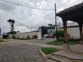 Una calle adoquinada con un edificio blanco identificado con el rótulo "CAR WASH" y un área techada con escalones que la conducen.