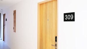 Un pasillo con una puerta de madera con el número 309, un timbre y un portero automático en la pared.