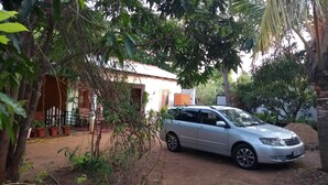 Un coche plateado estacionado en una entrada de casa, con una vivienda al fondo.