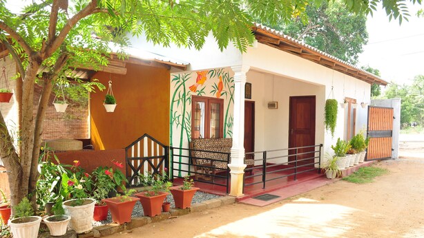 Una casa con porche, plantas en macetas y un mural.