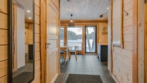 A wooden interior hallway leading to a dining area with a view of a snowy landscape. - Aulanko Lake Villa - Peace & Privacy (Hameenlinna)