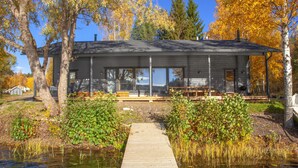 A cabin with a wooden deck leading to a dock over a pond, surrounded by autumn foliage. - Aulanko Lake Villa - Peace & Privacy (Hameenlinna)