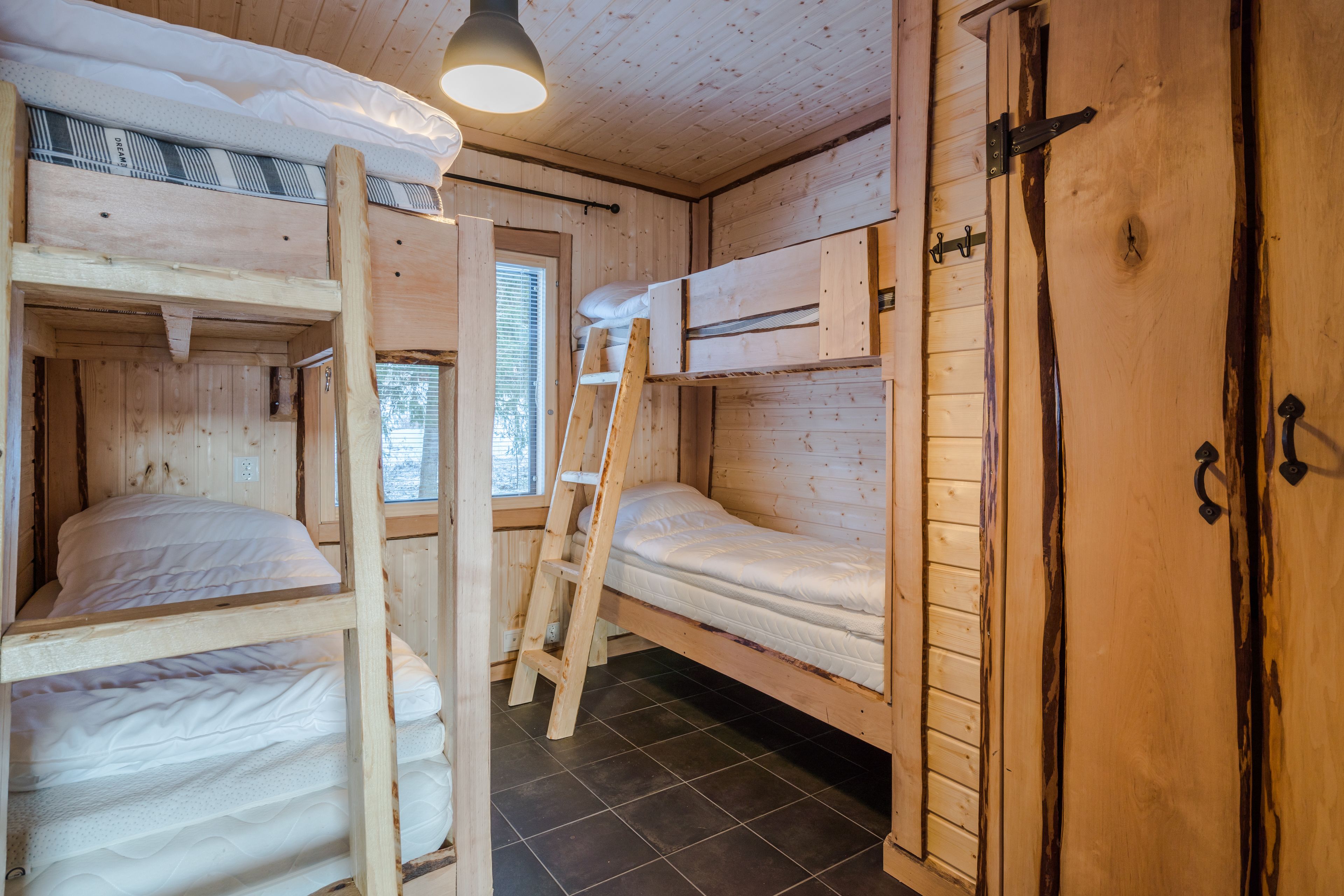 A wooden cabin with bunk beds, a ladder, and a door with a handle.