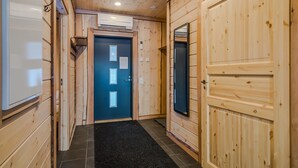 A wooden interior hallway with a blue door, a black mat at the entrance, and an air conditioning unit on the ceiling. - Aulanko Lake Villa - Peace & Privacy (Hameenlinna)