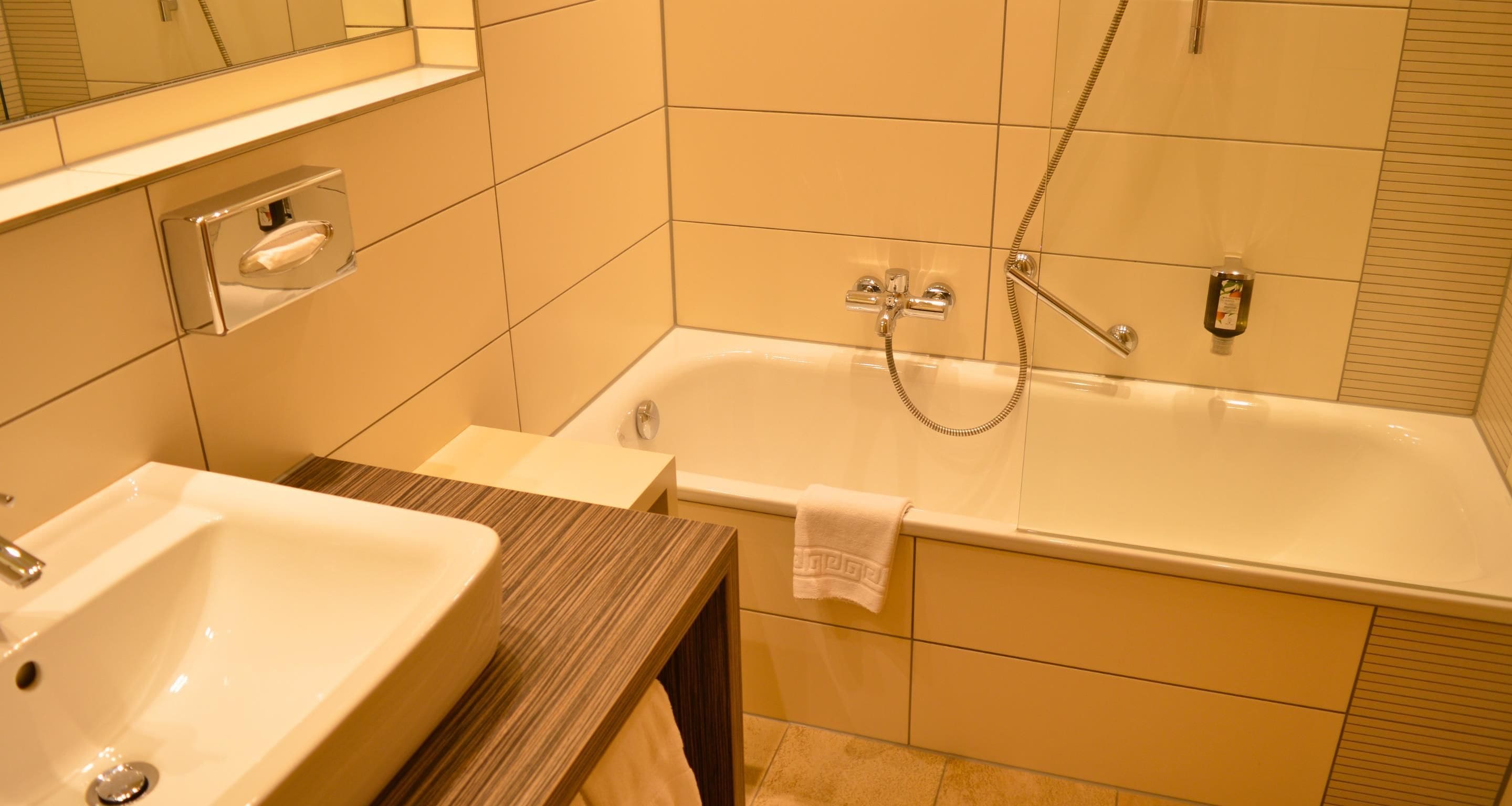 Een badkamer met een bad, een wastafel en een handdoekhouder.
