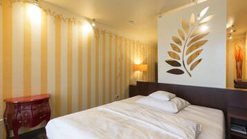 Een hotelkamer met een bed, nachtkastje, lamp en decoratief paneel.