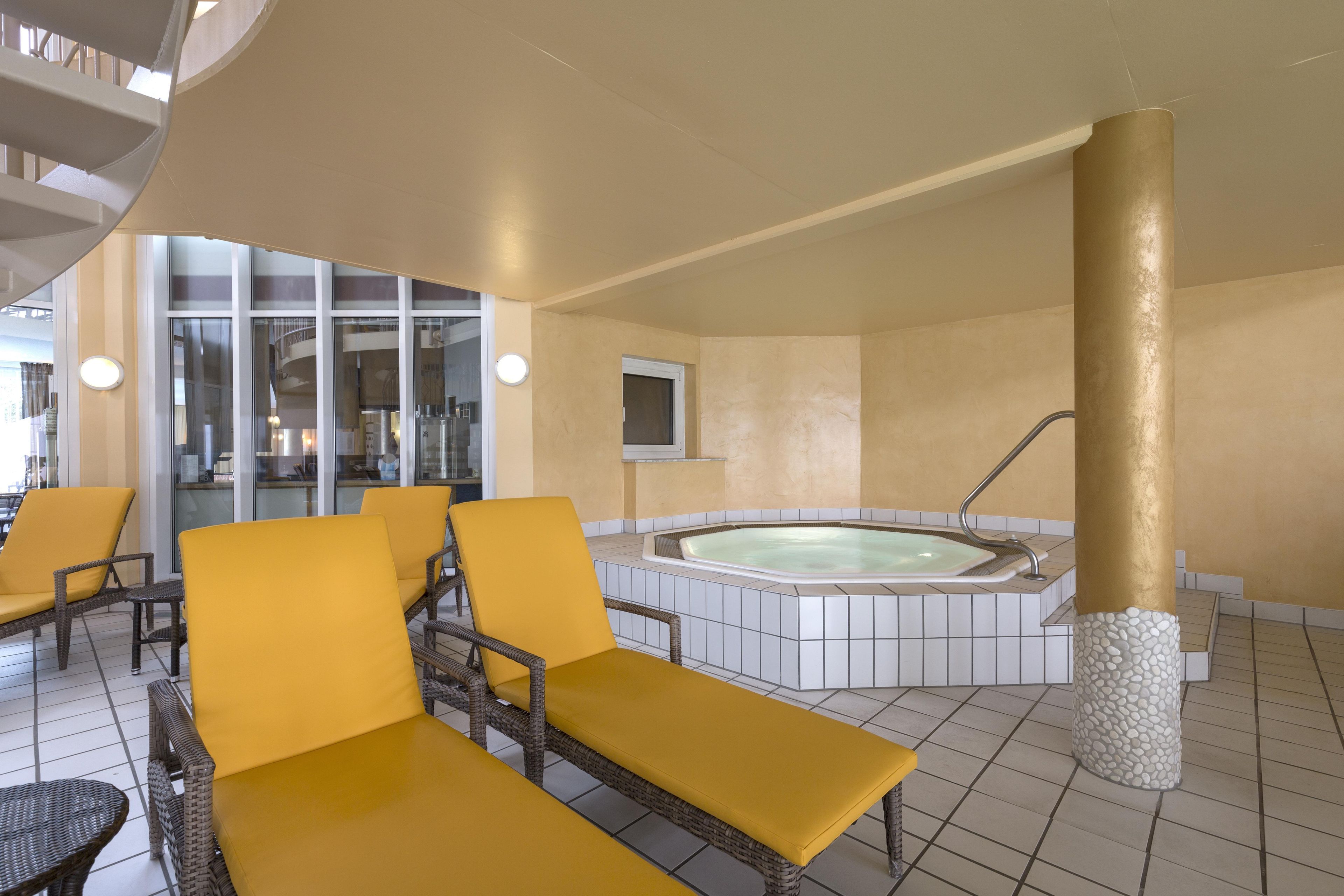 A spa area with a hot tub, yellow lounge chairs, and a stone pillar.