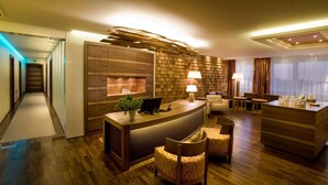 Un vestíbulo de hotel con una recepción, zona de estar y un revestimiento de pared de madera.