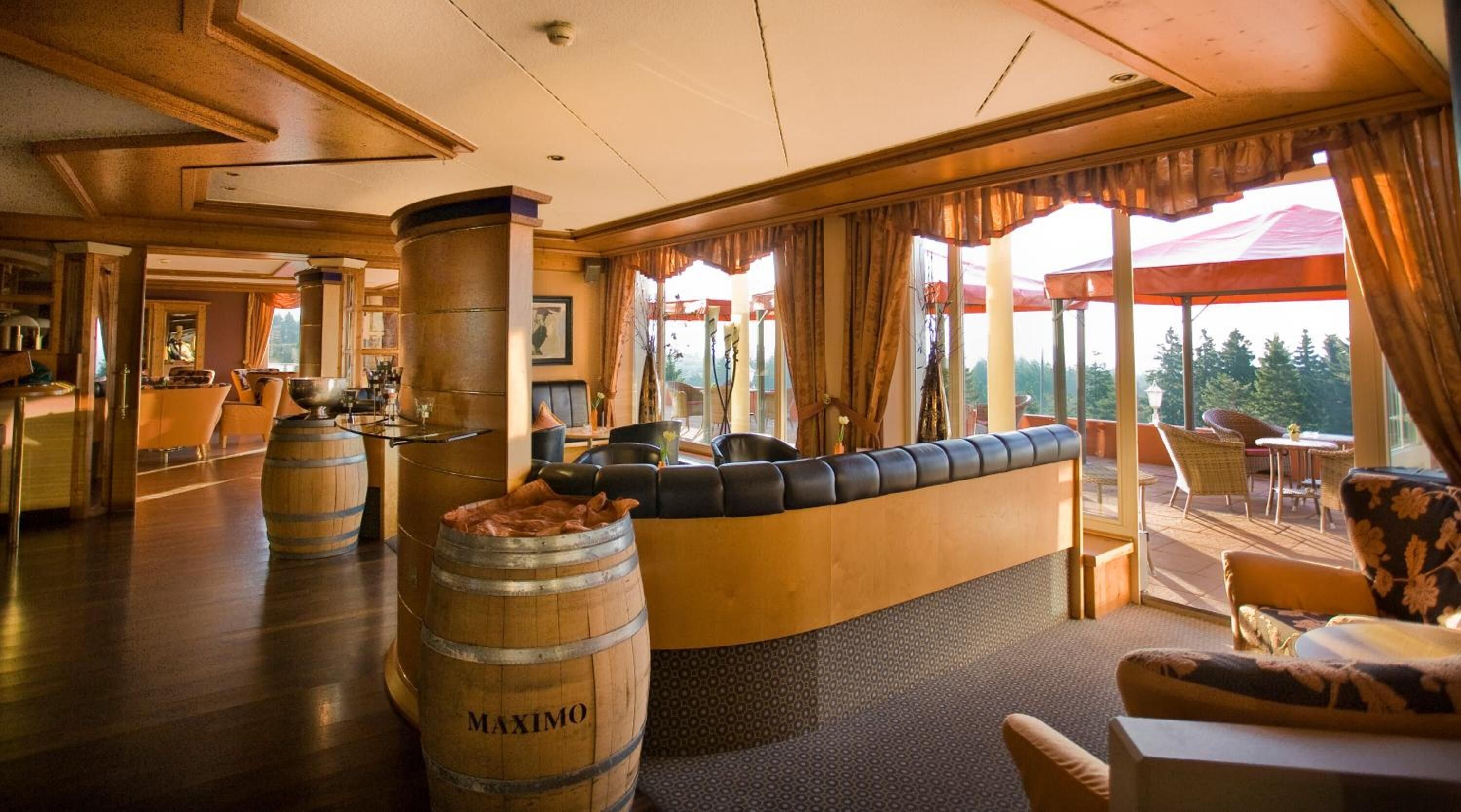 A spacious lobby with a bar area, leather seating, and large windows offering a view of the outdoors.
