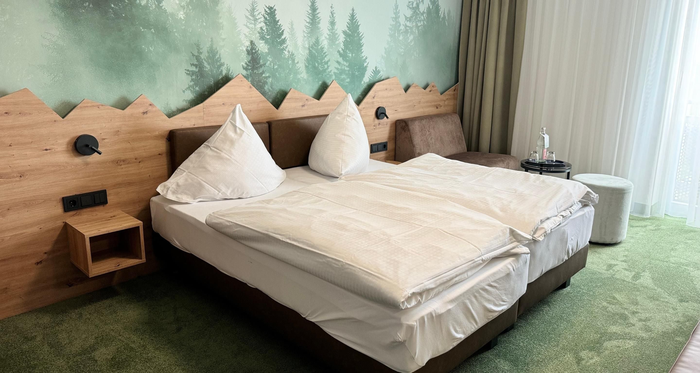 Una habitación de hotel con una cama, una mesita de noche, una pequeña mesa y un mural en la pared.