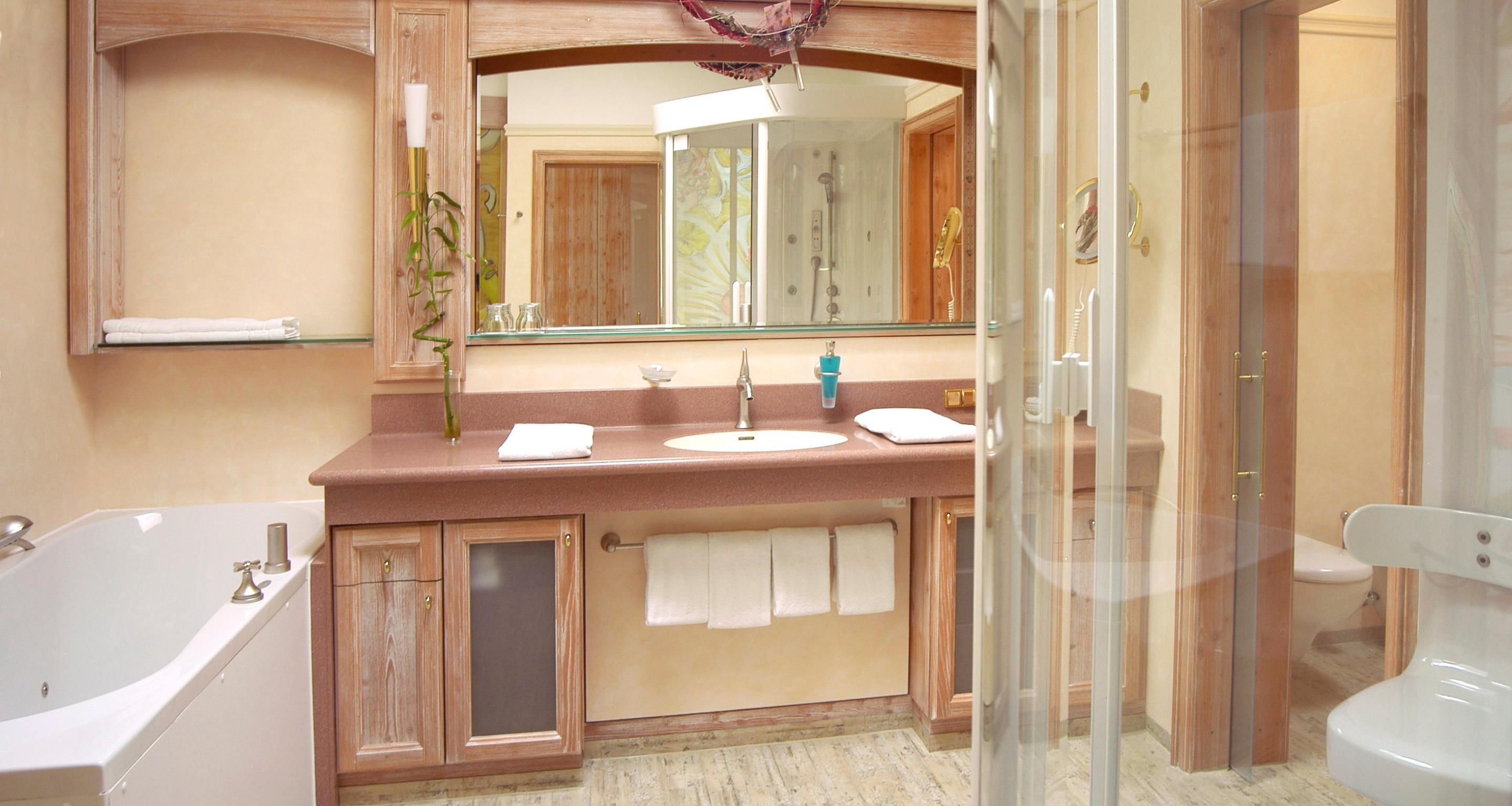 Un bagno con vasca, lavandino, specchio e doccia.