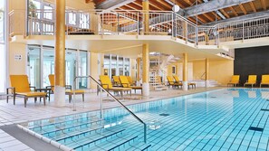 Una piscina con varios niveles, sillas de descanso amarillas y una escalera.
