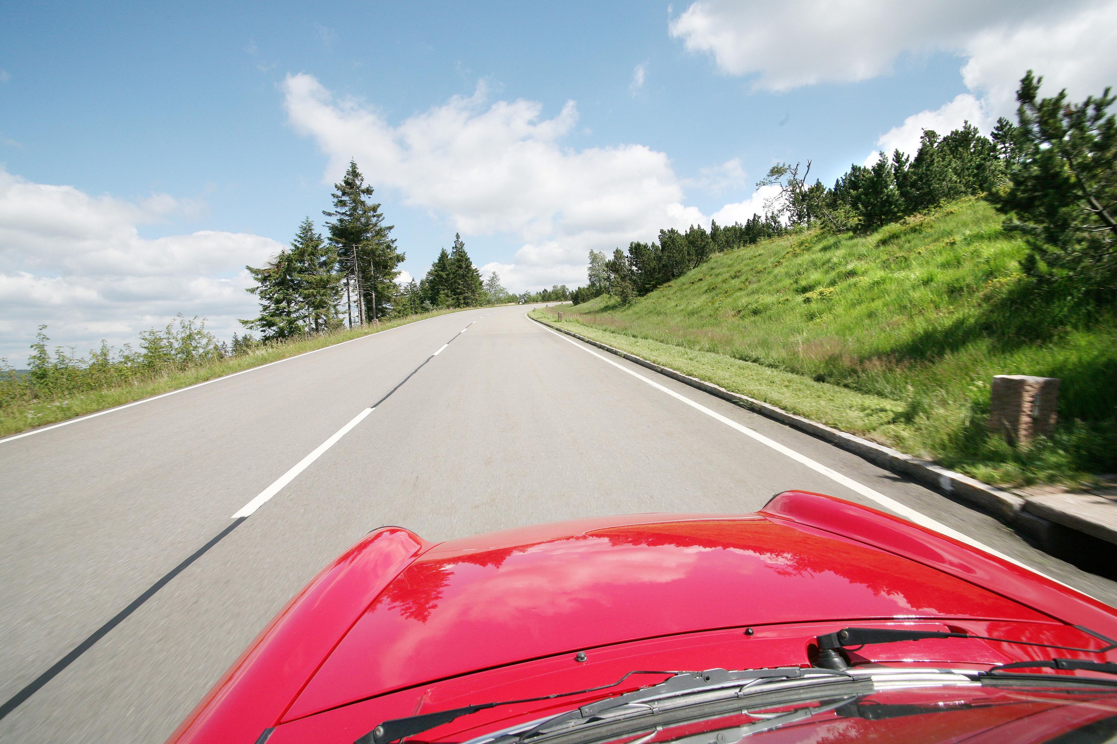 A road with a red car in the foreground.