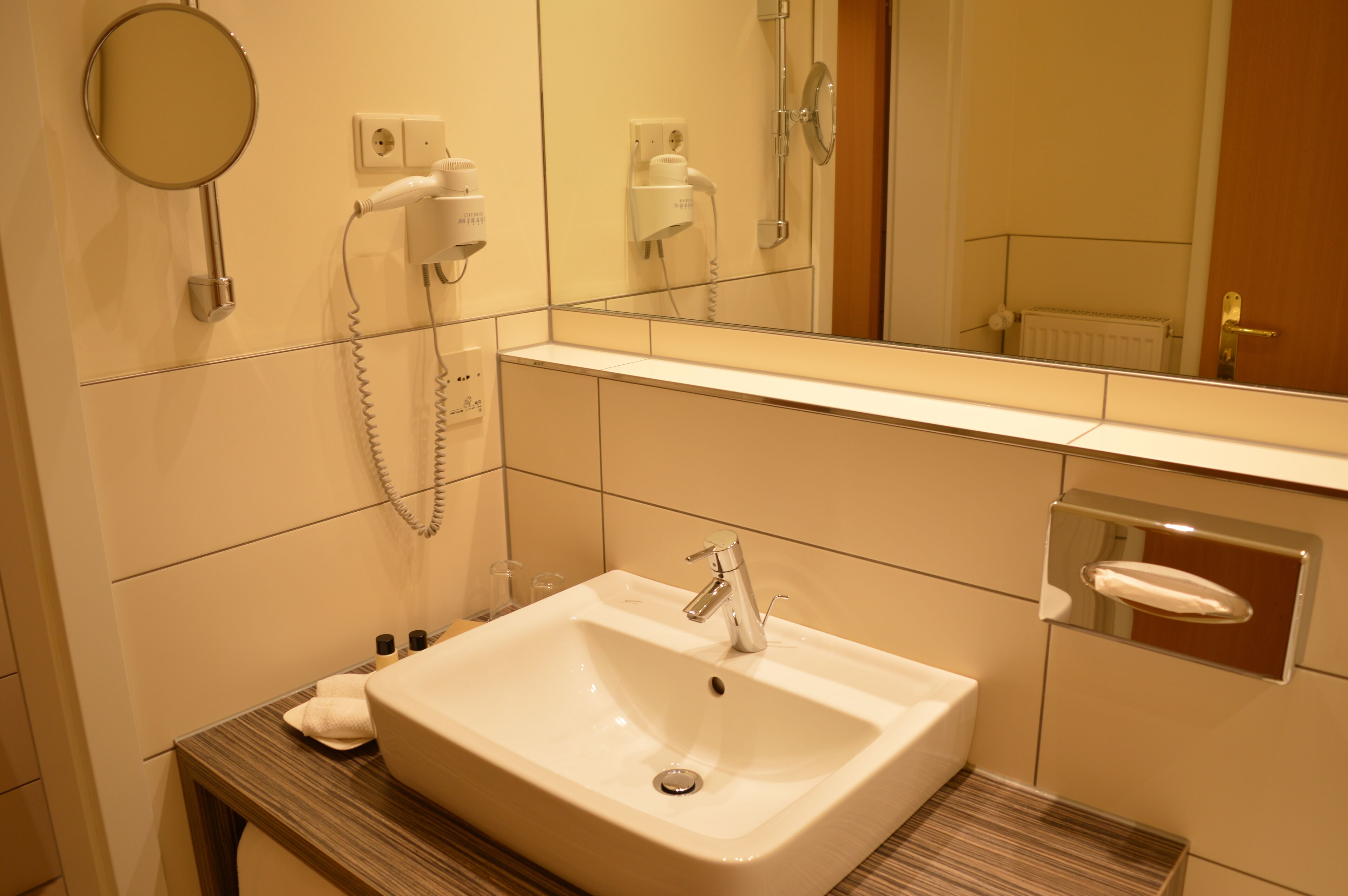 A bathroom with a sink, mirror, and hairdryer.