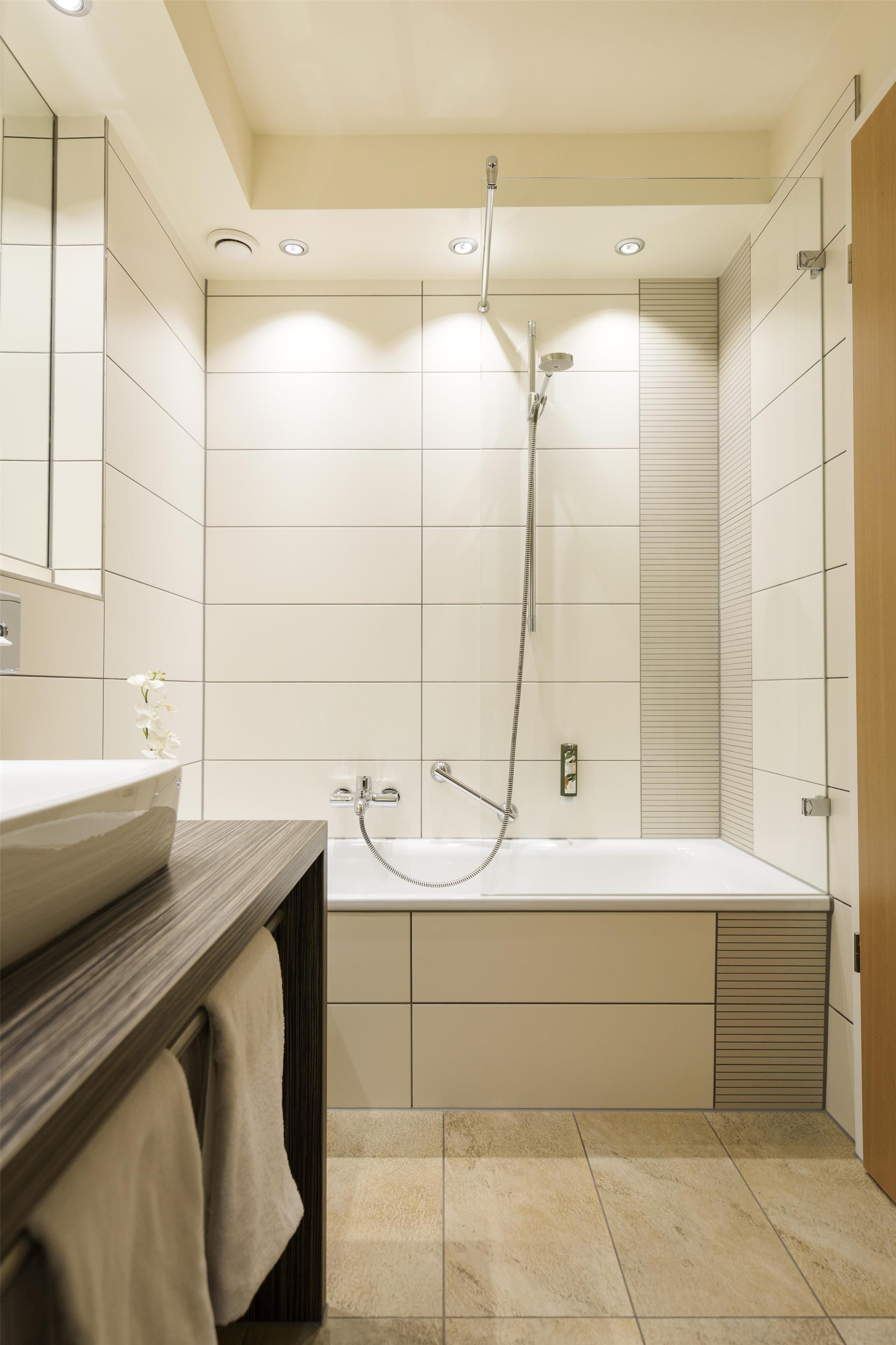 Une salle de bain moderne équipée d’une baignoire, d’une douche et d’un meuble-lavabo avec un miroir.