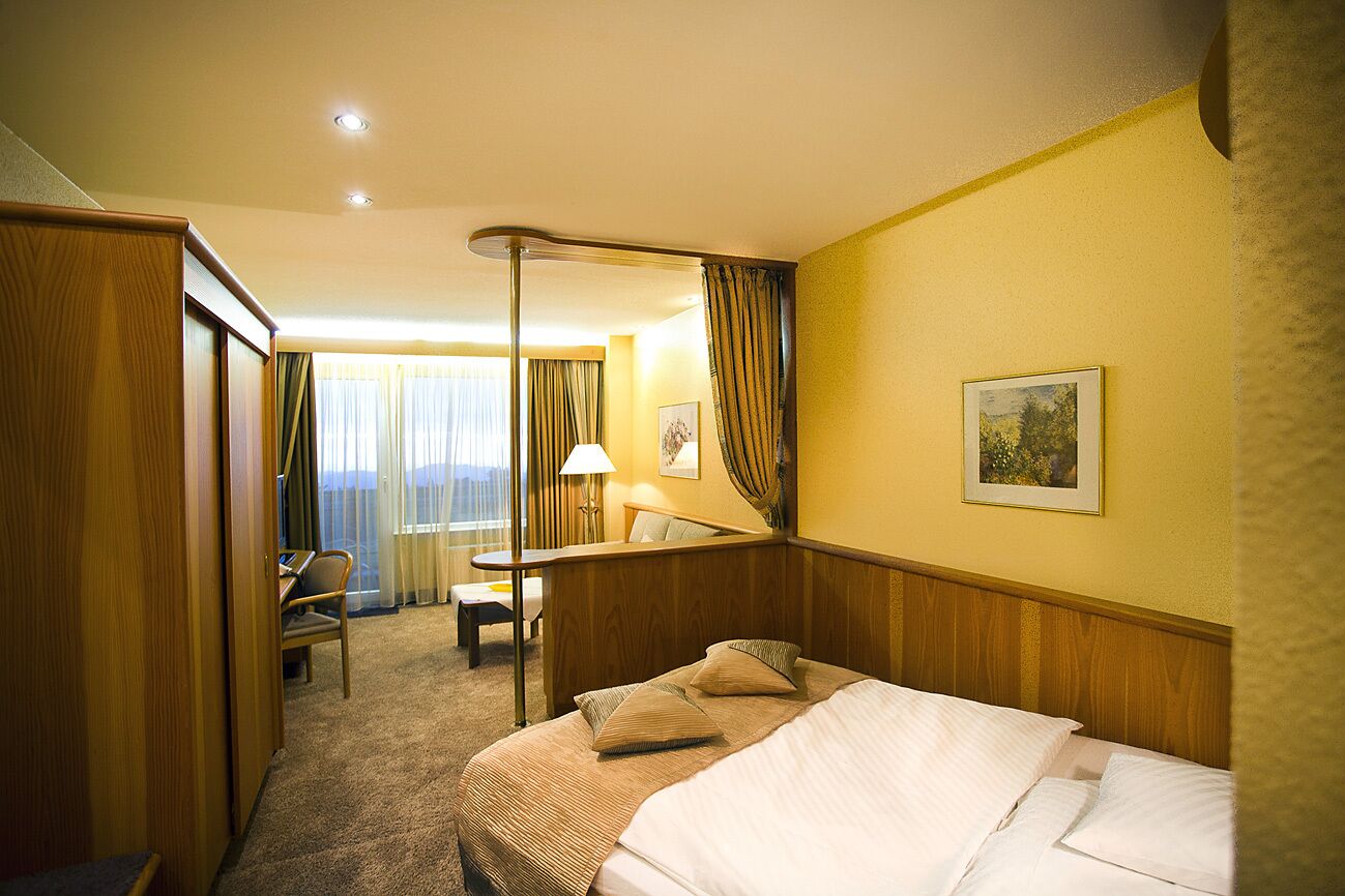 Ein Hotelzimmer mit Bett, Schreibtisch, Stuhl und Blick ins Freie.