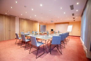 Un salón de conferencias con una larga mesa, varias sillas y una pizarra.