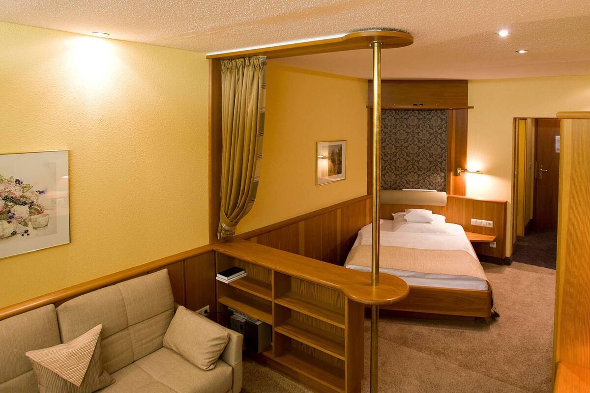 Une chambre d’hôtel comprenant un lit, un bureau, une chaise, une table de chevet, une lampe et une armoire.