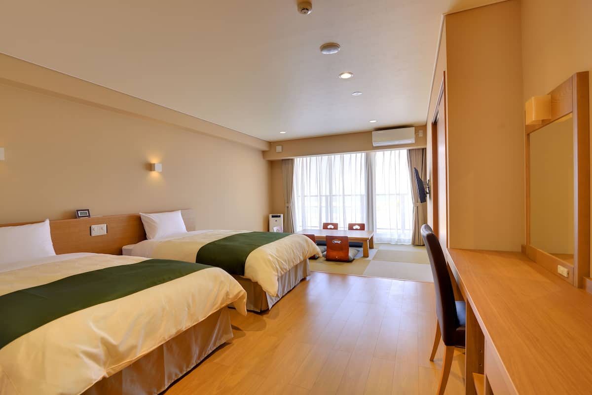 A hotel room with two beds, a desk, and a chair.