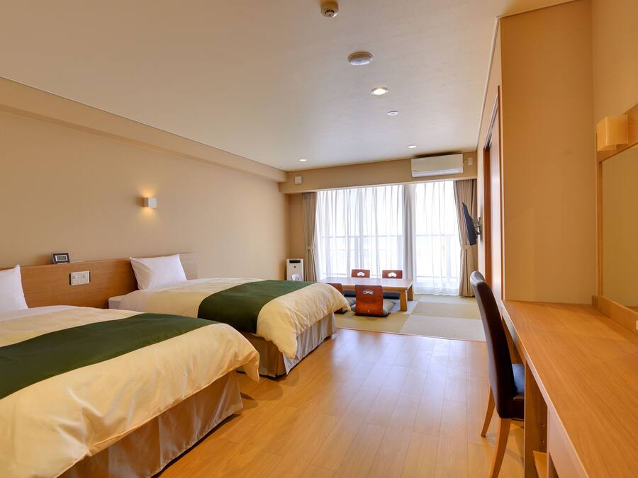 A hotel room with two beds, a desk, and a chair.