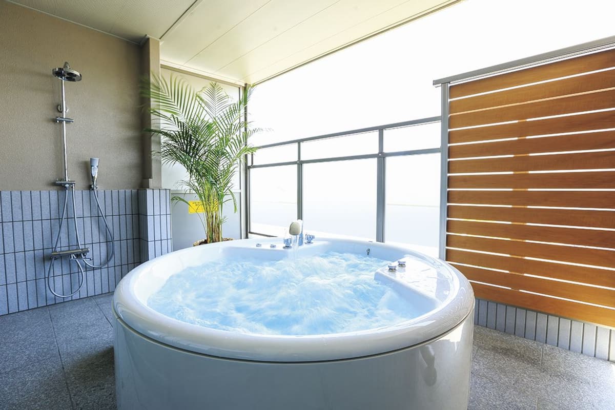 A modern bathroom with a large bathtub, a shower area, and a potted plant.