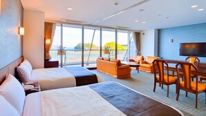 Une chambre d’hôtel avec deux lits, un canapé, une table à manger avec des chaises, une télévision et un balcon avec vue.