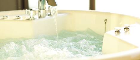 A bathtub with running water, a faucet, and a control knob.