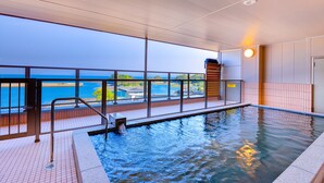 Une piscine intérieure avec vue sur la mer, une balustrade en verre et un sol carrelé.