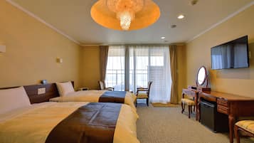 A hotel room with two beds, a desk with a mirror, a television, and a chandelier.