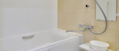 A modern bathroom with a white bathtub, a handheld showerhead, a sink with a bowl, and a mirror.