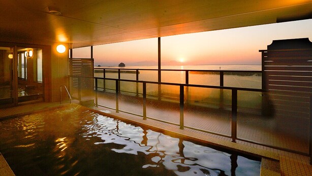 Une piscine intérieure offrant une vue sur le coucher de soleil sur l’eau.