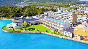 Un hôtel situé sur la côte, doté d’une piscine, un grand bâtiment à toit plat, avec une montagne en arrière-plan.