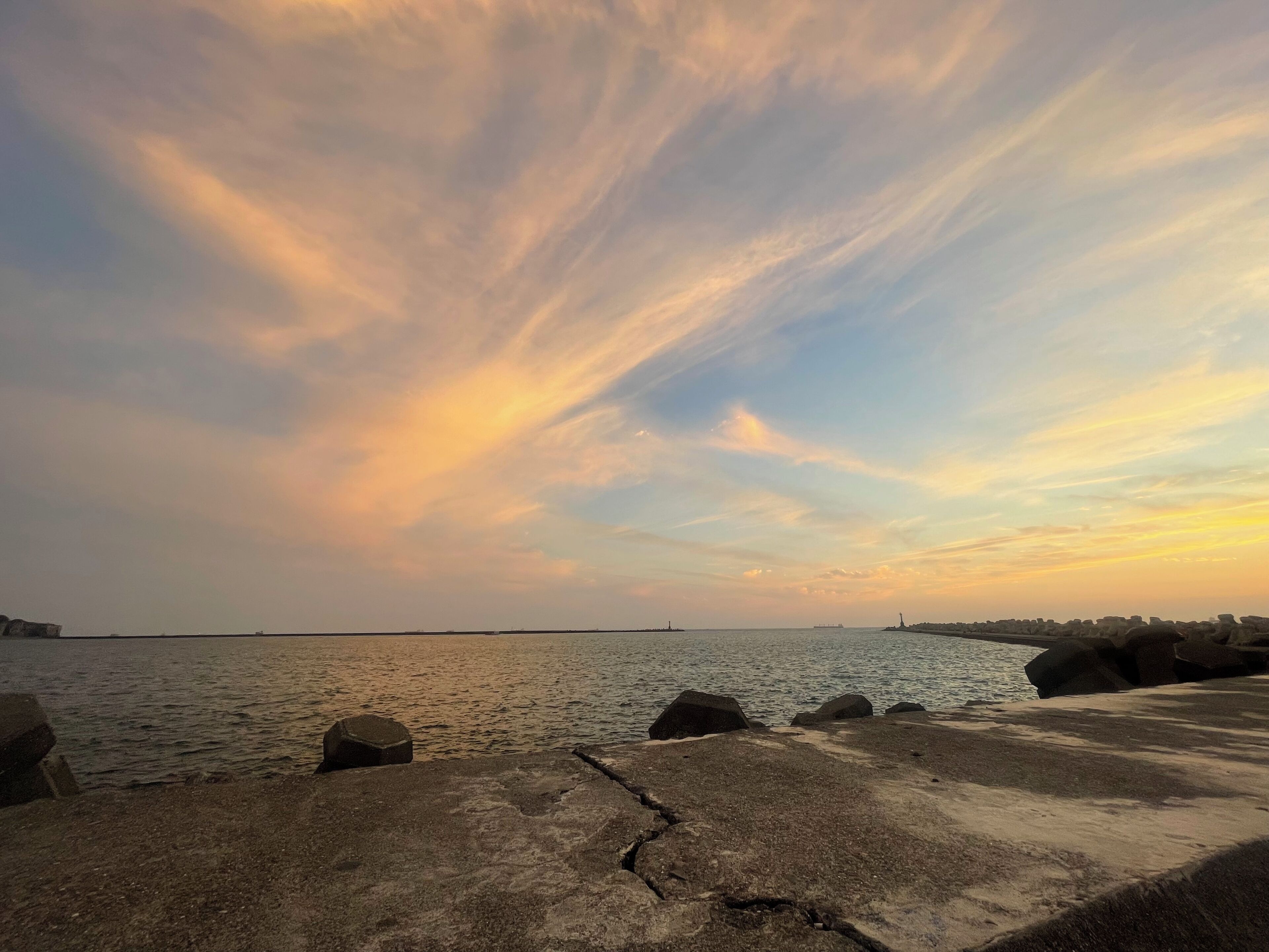 Un paisaje costero con un muelle de hormigón y rocas que se adentran en el agua.