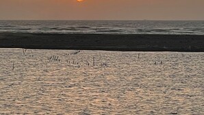 A sunset over a beach with calm waters and a clear sky. - LanJen Villa B&B (Tainan)
