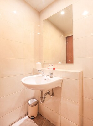 A bathroom with a white sink, mirror, and tiled walls. - OYO Flagship 755 Appartel Grand Dhika City (Bekasi)