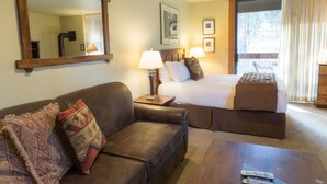 A hotel room with a bed, a sofa, a coffee table, and a large mirror. - 3160 Aspen Grove (Truckee)