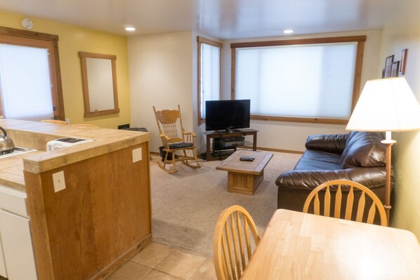 A compact living space with a kitchen area, a dining table, a sofa, and a television. - 4081 Ski Trails (Truckee)