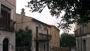 A narrow street with historic buildings, some with balconies and plants. - B&B Mamma Elena (Rovito)