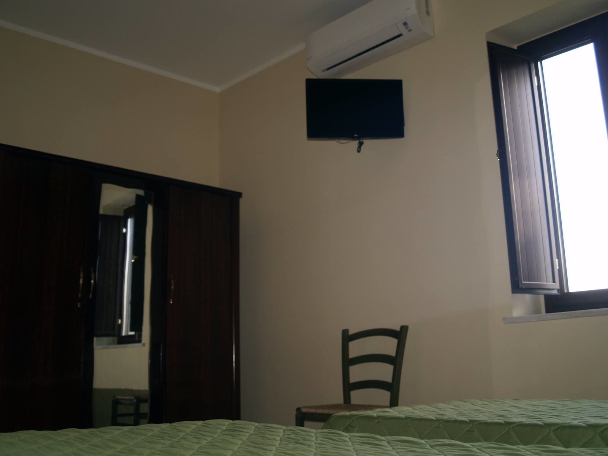 Una camera da letto con un letto, una sedia, un armadio, un condizionatore d'aria e una finestra.