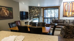 A dining area with a stone wall, a television, and a painting of a bear.