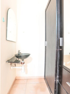 Une salle de bain avec un lavabo, un miroir et une porte.