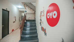 Eine Treppe mit Handlauf, eine Wand mit einem roten Rundschild und eine Tür.