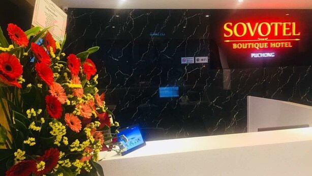A reception desk with a black marble wall, a neon sign for 'SOVOTEL Boutique Hotel', a 'No Smoking' sign, and a 'WiFi' sign. - Sovotel 9 Puchong (Puchong)