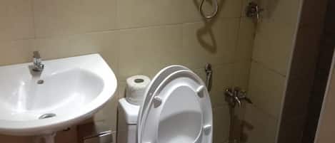 Un baño con lavamanos, inodoro y ducha blancos.