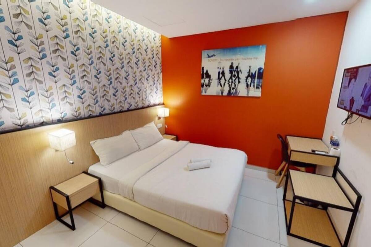 Habitació d'hotel amb llit, taules de nit, televisió i un cartell a la paret.